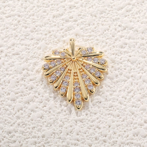 Elegant gold leaf pendant with clear zircon inlay on a beige textured background