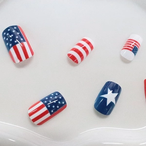 Glossy American flag press-on nails with red stripes and blue star patterns on white tray