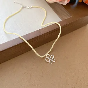 Collana di perline di cristallo crema con ciondolo a fiore in zircone su sfondo elegante
