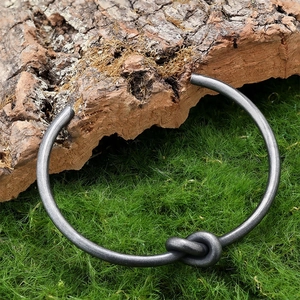 Retro open stainless steel knot cuff bracelet with antique silver finish on natural moss