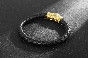 Close-up of braided black leather bracelet with golden lion head magnetic clasp