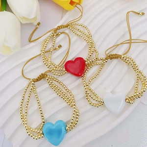 Detalle de pulseras de cuentas de oro hechas a mano con dijes de corazón de vidrio