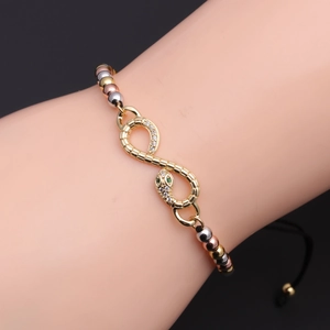 Detail of infinity snake bracelet with white zircons and tri-color metal beads