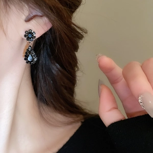 Close-up of elegant black teardrop gemstone earrings worn by model for a luxury look