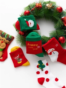 Close-up of cotton Christmas socks with reindeer and Santa motifs on holiday wreath