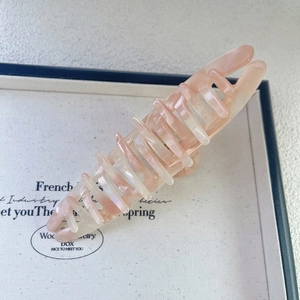 Detailed view of 13.5cm large acetate hair claw with pink marble texture and pearlescent finish