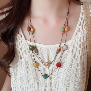 Dettaglio di perline in ceramica colorata e conchiglie su una collana boho a doppio strato