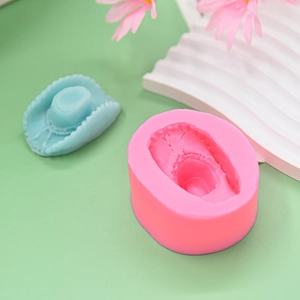 Pink silicone mold for cowboy hat design with blue resin finished sample on green background