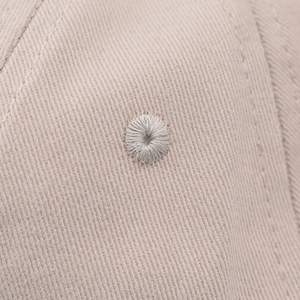 Close-up of embroidered ventilation eyelets on a beige twill cotton baseball cap