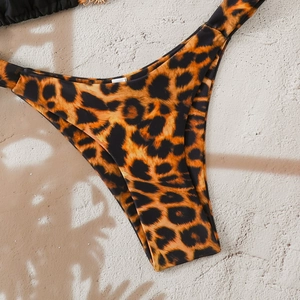 Close-up of leopard print bikini bottoms with metal hardware on textured stone surface