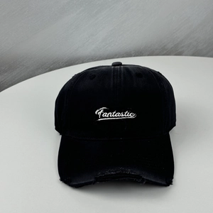 Gros plan sur la visière usée et la broderie blanche Fantastic de la casquette noire