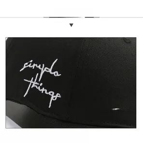 Close-up of white script embroidery on black twill cotton baseball cap fabric