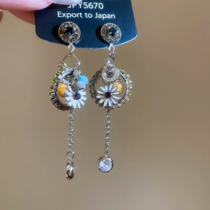 Detail of daisy flower earrings with sparkling rhinestones and colorful bead tassels