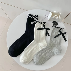 Detailed view of ribbed knit socks with elegant ruffles and bow in black white and grey