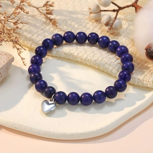 Macro detail of blue natural stone beads and silver heart charm on an elegant bracelet