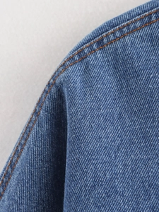 Detailed close-up of blue denim fabric showing orange contrast stitching and twill texture