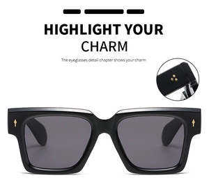 Detail view of black square sunglasses with gold arrow accents and triple-star studs on temples