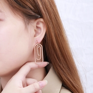 Detail of rose gold multi-layered oval drop earrings on model showing spiral design