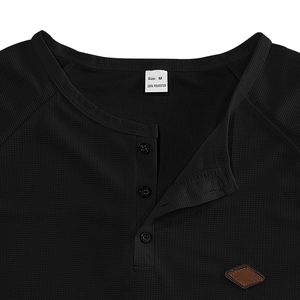 Detail of waffle knit fabric and three-button henley neckline on black polyester shirt