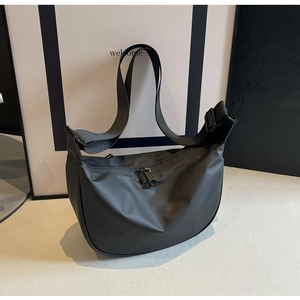 Detail of black nylon dumpling crossbody bag with adjustable wide strap and dual zippers