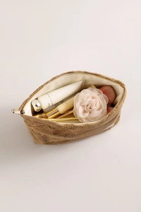 Detail of floral embroidery on linen cosmetic bag with golden metal zipper closure