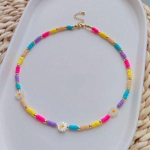 Detailed macro view of colorful heishi beads and daisy charms on a boho necklace