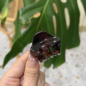 Detailed view of small amber resin hair claw clip with transparent tortoiseshell texture