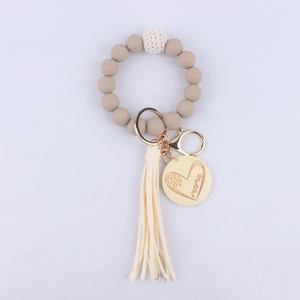 Detail of khaki silicone bead keychain with beige tassel and engraved Mama heart pendant