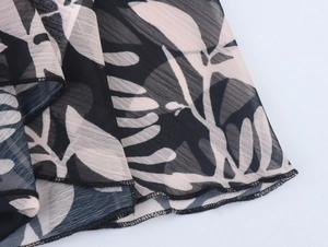 Detail of leaf print chiffon fabric showing translucent texture and professional overlock stitching