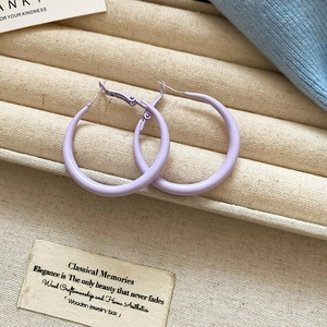 Macro detail of lavender purple round hoop earrings on beige velvet jewelry display