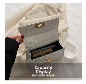 Detail showing white crocodile pattern crossbody bag interior with phone and wallet