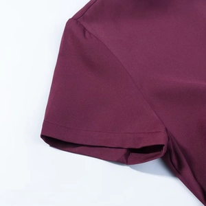 Détail de la couture d'un revers de manche bordeaux sur un haut à manches courtes
