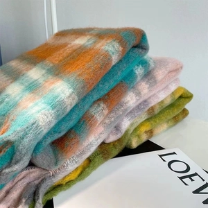 Close-up of neatly folded plaid mohair scarves featuring soft textures and tassels