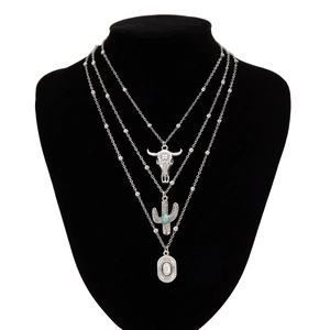 Detail of bohemian layered necklace with vintage silver bull head and cactus pendants