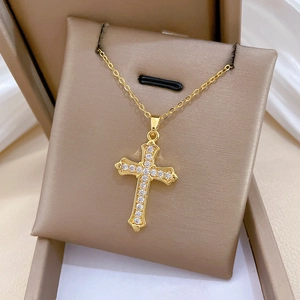 Close-up of golden cross necklace with pavé cubic zirconia on a luxury jewelry box
