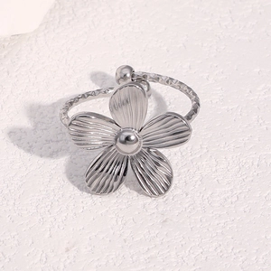 Detail of silver stainless steel flower ring with rope band on a marble background