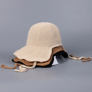 Detail of woven straw sun hats in beige, brown and black with lace-up chin straps