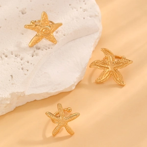 Detailed view of three golden starfish ear cuffs with textured metal on stone blocks