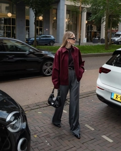 Street style view of a burgundy zipper jacket with collar and grey striped trousers