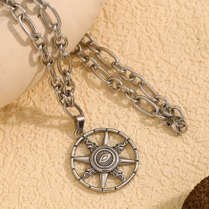 Close-up of silver retro sun and evil eye pendant on a thick stainless steel Cuban chain