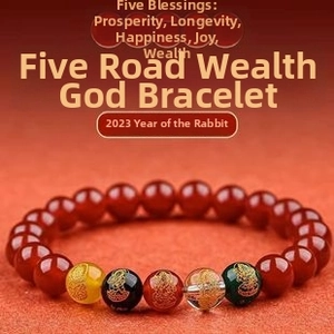 Macro detail of Five Roads Wealth God bracelet with red beads and engraved talismans