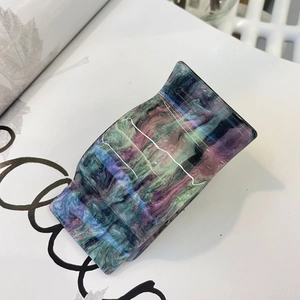 Macro detail of acrylic hair claw clip with purple and green marble texture finish
