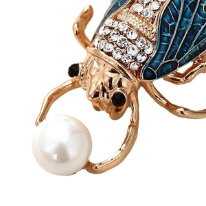 Exquisite golden insect brooch with blue enamel wings and a large white faux pearl accent