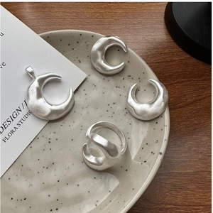Detailed close-up of matte silver moon jewelry set with hand-hammered texture on ceramic tray