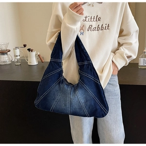 Détails de sac bandoulière en denim bleu foncé avec surpiqûres et fermeture éclair
