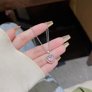 Close-up of pink heart-shaped pendant with white crystals on a silver chain