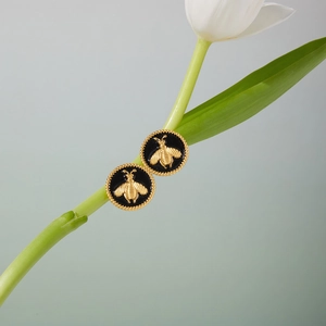 Détail de boucles d'oreilles en or 18 carats avec émail noir et relief d'abeille dorée