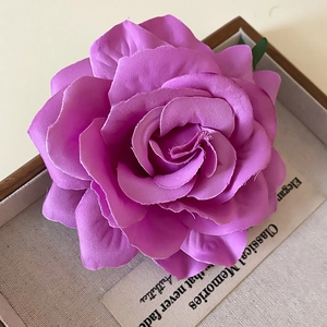 Detailed close-up of a violet silk fabric rose pin placed on a wooden rustic tray