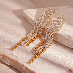 Détail de boucles d'oreilles pampilles dorées avec oxydes de zirconium sur pierre naturelle