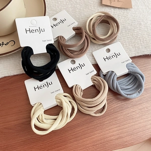 Macro detail of multi-colored elastic hair tie set on a minimalist branded display card